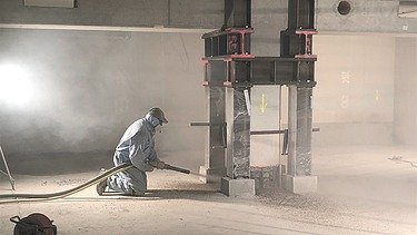 Foto von einer Person in Schutzausrüstung mit einer Spritzbetonlanze