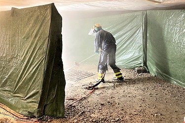 Foto einer Person mit Schutzbekleidung und Strahllanze in der Hand